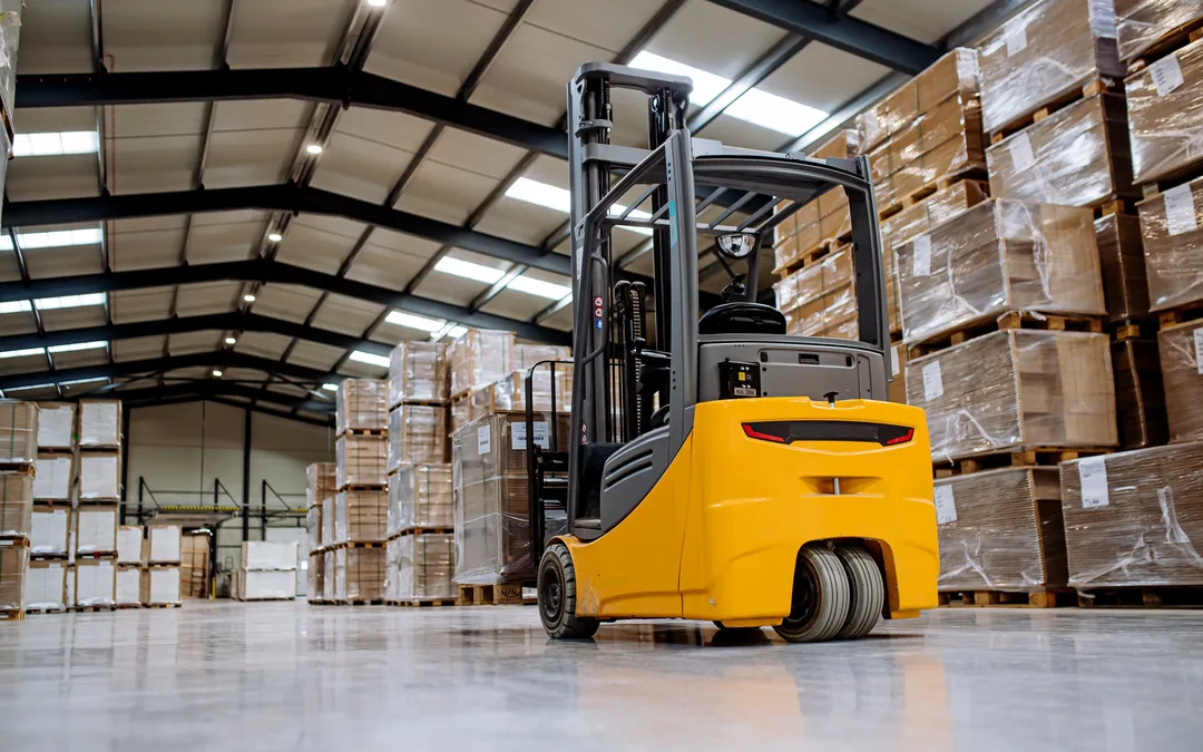 A forklift standing in a warehouse aisle between tall racks of palletised stock — forklift insurance in Ohio